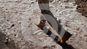 Camera pursues human foot that is on the dirty snow in the afternoon.