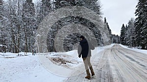 Camera pursues a man who goes on winter road and dances.