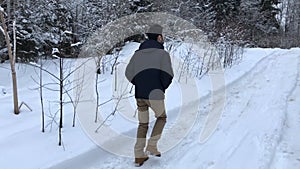 Camera pursues the man who walks on the winter road in the daytime.