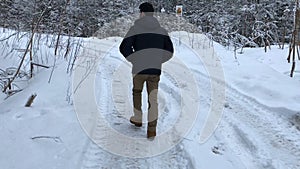 Camera pursues the man who walks on the winter road in the daytime.