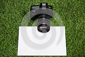 Camera with sheet of paper lying on grass