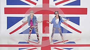 Camera shows rehearsal of two funny girls moving on background of UK flag