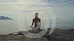 Camera shows sitting girl back silhouette against ocean