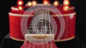 Camera slide along the neck of a red acoustic guitar