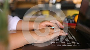 Camera slides around female freelancer's hands typing on laptop keyboard in cafe. Businesswoman working at office