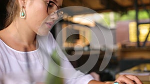 Camera slides around female freelancer's hands typing on laptop keyboard and rises to her face. Mixed race