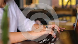 Camera slides around female freelancer's hands typing on laptop keyboard and rises to her face. Mixed race