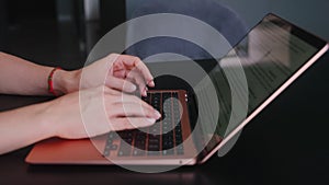 Camera slides around female freelancer's hands typing on laptop keyboard in slow motion. Business woman working at