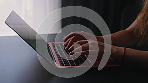 Camera slides around female freelancer's hands typing on laptop keyboard in slow motion. Business woman working at