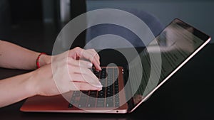 Camera slides around female freelancer's hands typing on laptop keyboard in slow motion. Business woman working at
