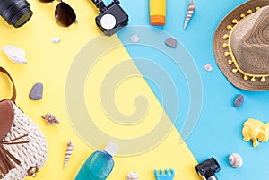 Camera, straw hat, sunblock, lens, straw bag and seashells on a yellow background.