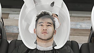Camera top view Asian man`s hairdresser washes the client`s head