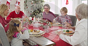 Camera tracks down to show extended family group sitting around table and enjoying Christmas meal