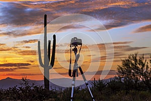 Camera On Tri Pod With Desert Sunrise In Background