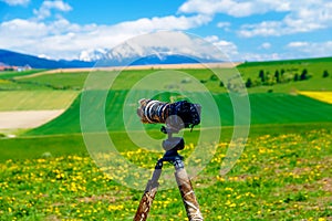 Camera on a tripod in the beautiful landscape of spring snow mountains.