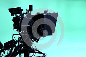 The camera on the tripod, led floodlight, prompter and a monitor on a green background.