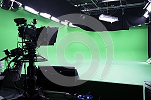 The camera on the tripod, led floodlight, prompter and a monitor on a green background.