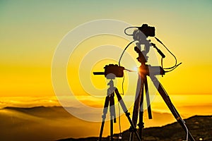 Camera on tripod take photo from sunset above clouds