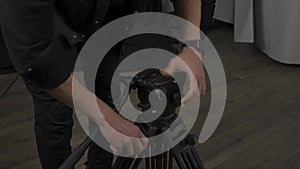 A cameraman opens and sets a tripod for a professional camera in a studio. Detail of the shooting process in close up.