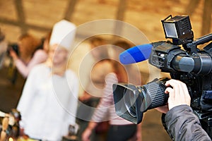 Cameraman operating video camera at news event