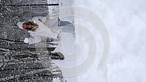 Cameraman playing snowballs with active beautiful young woman in snowy winter forest