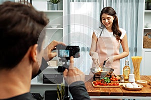 Cameraman recording to woman in chef influencer cooking spaghetti. Postulate.