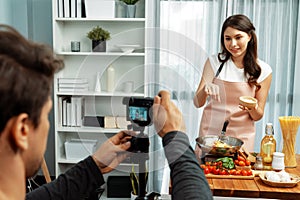 Cameraman recording to woman in chef influencer cooking spaghetti. Postulate.