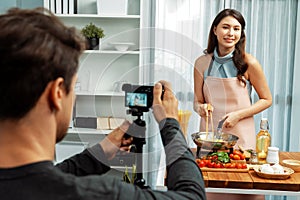 Cameraman recording to woman in chef influencer cooking spaghetti. Postulate.