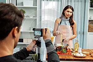 Cameraman recording to woman in chef influencer cooking spaghetti. Postulate.