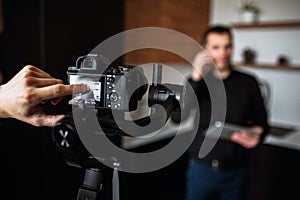 Cameraman`s finger point on camera`s screen. Recording video or taking picture of young buisnessman in kitchen talking