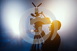 Cameraman silhouette on a live studio news stage.Professional cameraman with headphones in television news broadcast