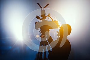 Cameraman silhouette on a live studio news stage.Professional cameraman with headphones in television news broadcast photo