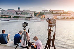 Cameras on tripods photograph a bridge and a river