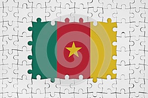 Cameroon flag in frame of white puzzle pieces with missing central part