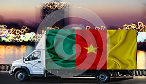 Cameroon flag on the side of a white van against the backdrop of a blurred city and river. Logistics concept