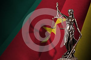 Cameroon flag with statue of lady justice and judicial scales in dark room. Concept of judgement and punishment