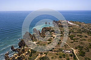 Camilo Beach and Ponta da Piedade in Lagos, Algarve - Portugal. Portuguese southern golden coast cliffs. Sunny day aerial view