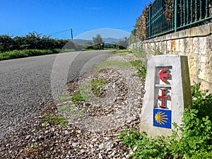 Camino Lebaniego sign: Traditional shell sign and arrow painted on the way. Direction sign for pilgrims in Saint James way
