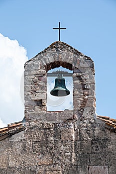 Sardinia. San Giovanni Suergiu. Palmas. Ancient Church of Santa Maria di Palmas, 11th century AD. Belfry with bell and iron cross photo