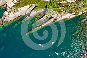 Camogli rocky coast aerial view. Boats and yachts moored near harbor with green water
