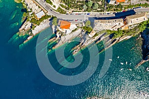 Camogli rocky coast aerial view. Boats and yachts moored near harbor with green water