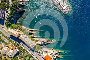 Camogli rocky coast aerial view. Boats and yachts moored near harbor with green water and lighthouse.
