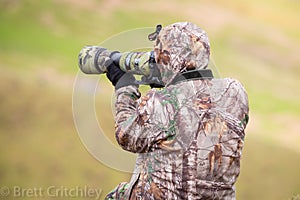 Camouflaged photographer using camera