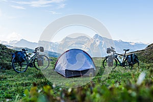Camp on a bike travel with two loaded bikes with panniers and a tent in between on a mountain pass in the Swiss alps