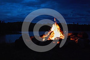 Camp fire burning in a fire pit next to the lake