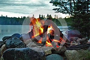 Camp fire burning in a fire pit next to the lake