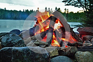 Camp fire burning in a fire pit next to the lake