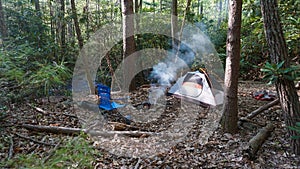 Camp kettle in the Blue Ridge Mountains in Asheville, North Carolina. Outdoor lifestyle with axe, cast iron skillet, flannel blan