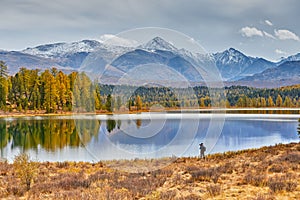 Camp in the mountains by the lake. Beautiful autumn landscape. The photographer walks along the shore and makes shots of