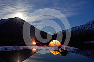 Camp near the mountain lake. Night landscape with a tent near the water. photo